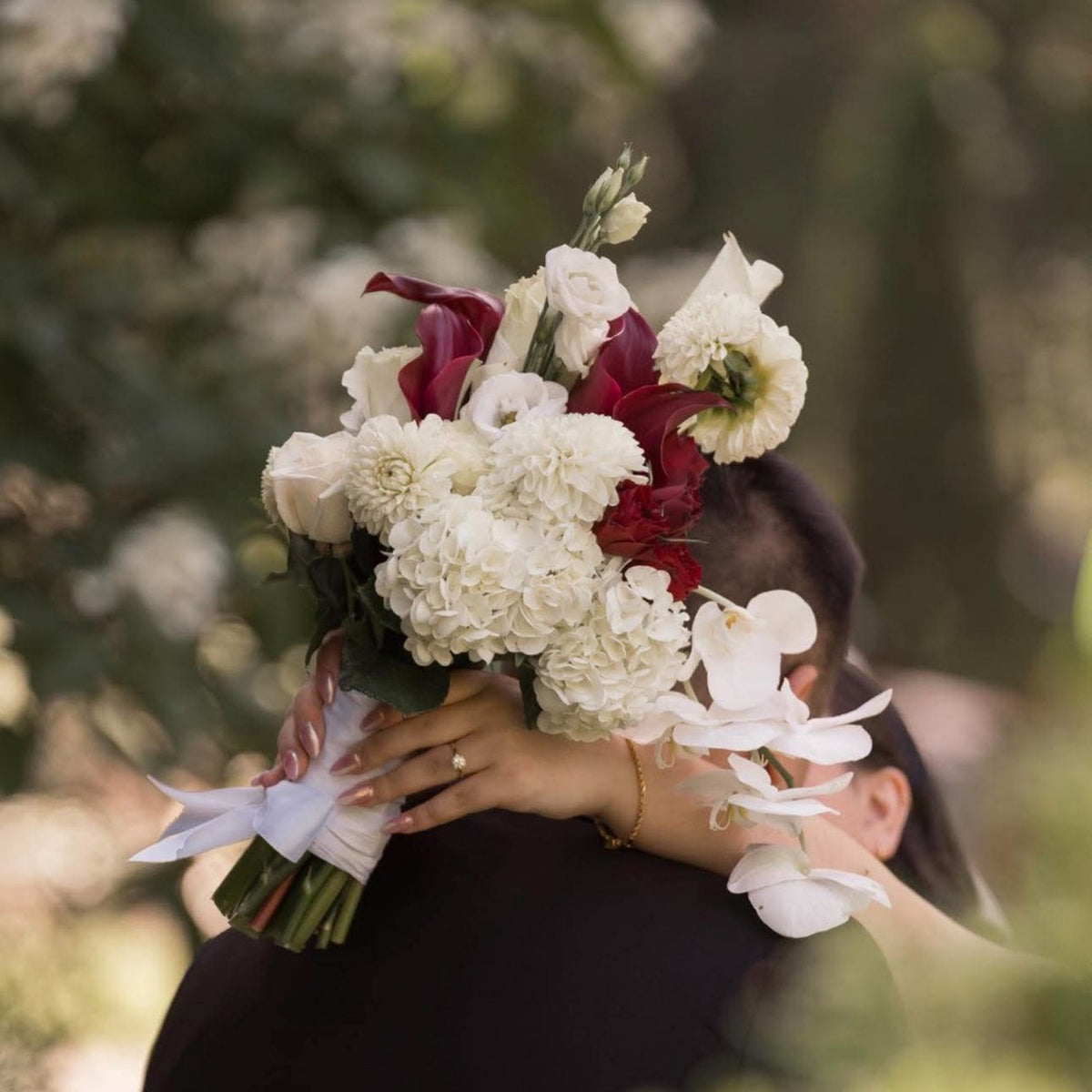 Bouquet de mariée blanc et bordeaux, fleurs blanches et orchidées, photographié en extérieur